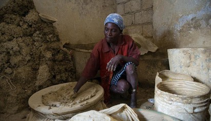 窮到吃土! 海地貧民「泥土餅乾」果腹 | 1名婦女正準備製作「泥餅乾麵糊」(翻攝網路)